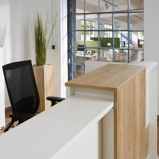 Tresenelement aus weißem Holz mit Holzelement vor schwarzem Schreibtischstuhl