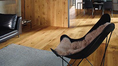 Holzwandverkleidung Wandverkleidung passend zu Bodenfarbe aus Holz mit Sessel im Vordergrund