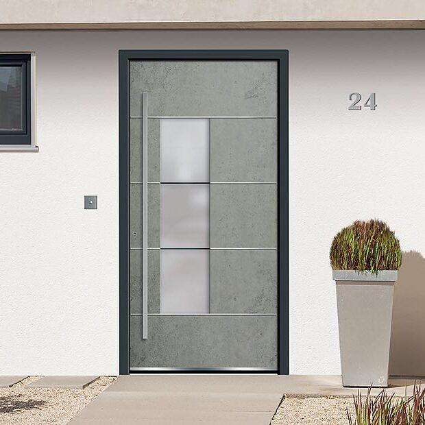 Graue Haustür in Betonoptik mit schwarzem Rahmen vor weißer Wand