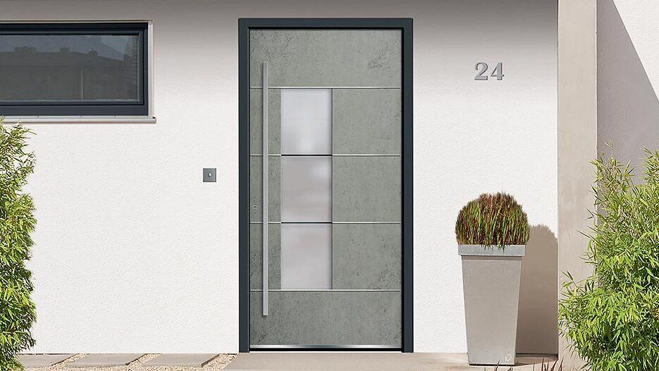 Graue Haustür in Betonoptik mit schwarzem Rahmen vor weißer Wand