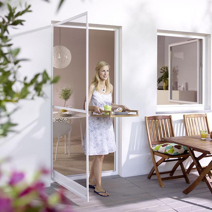 Frau, die durch Insektenschutz Schwingtür auf die Terrasse tritt