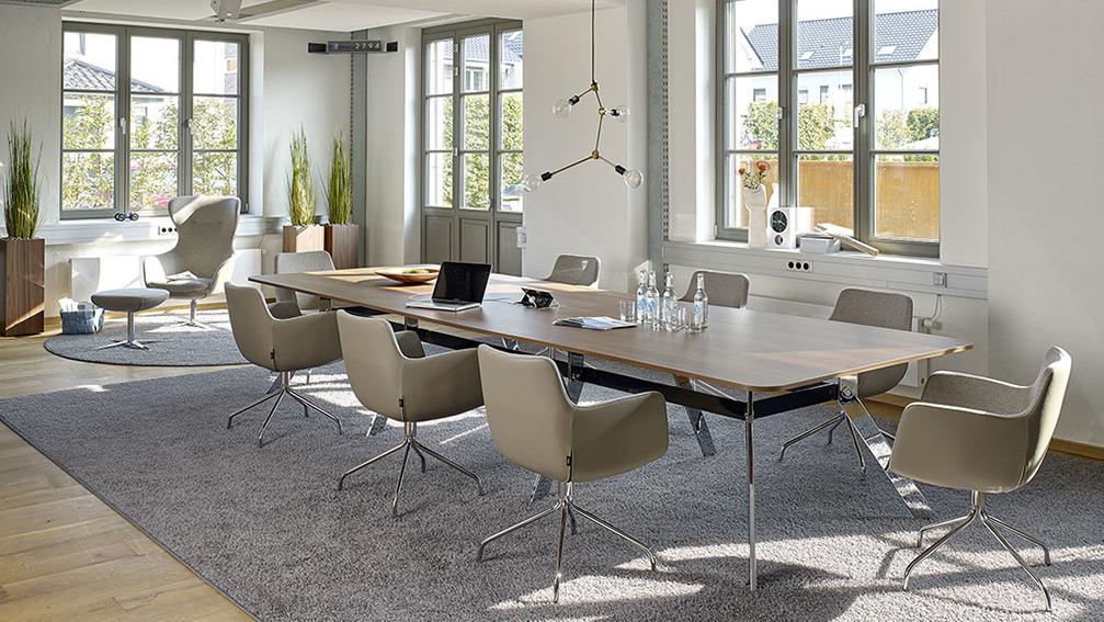 Konferenzraum mit moderner Einrichtung Langer Konferenztisch mit acht Plätzen vor Sprossenfenstern