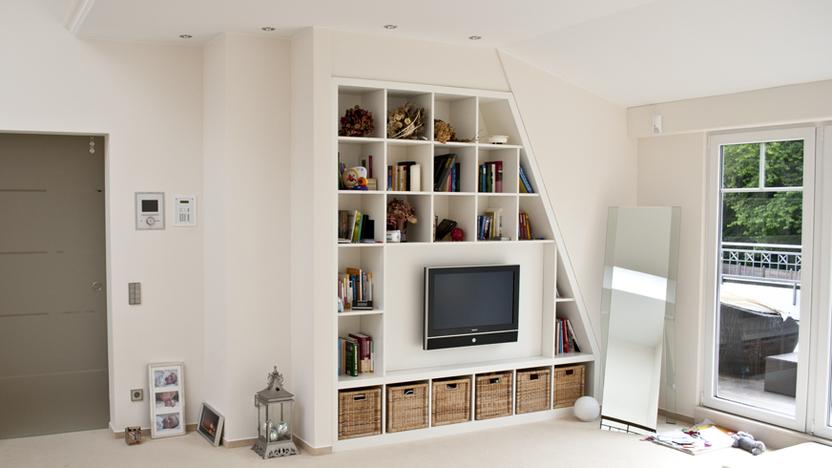Weißer Einbauschrank um Fernseher mit leichter Schräge