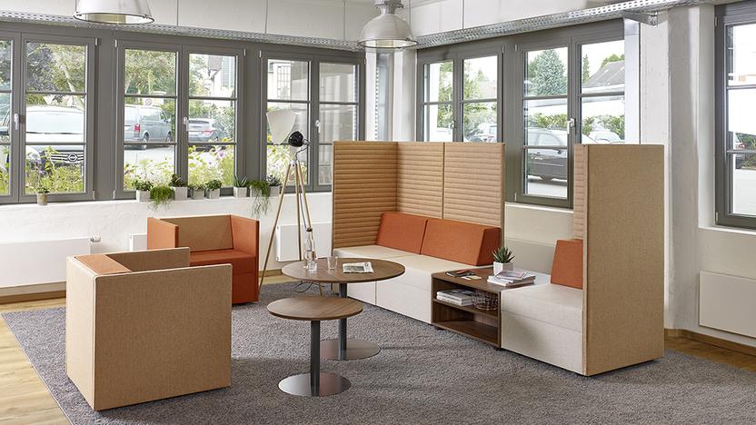 Drei Loungeelemente in Brauntönen um zwei runde Tische