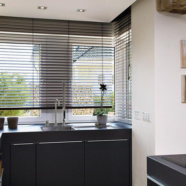 Innenliegende Holzjalousien vor Fensterfront als stilvoller Sonnenschutz im Wohnbereich