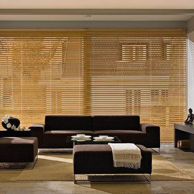 Großes Wohnzimmer mit Holzjalousien als natürlicher Sonnenschutz an breiter Fensterfront