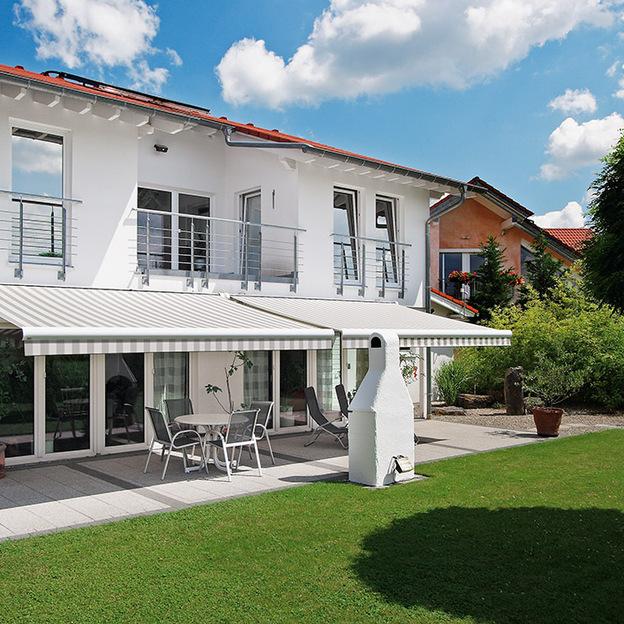 Gestreifte Markise als effektiver Sonnenschutz über der Terrasse eines modernen Einfamilienhauses