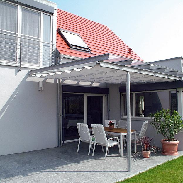 Pergolamarkise mit Wellenmuster als Sonnenschutz über möblierter Terrasse eines Einfamilienhauses