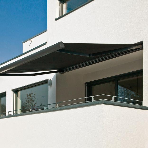 Moderne schwarze Kassettenmarkise als Sonnenschutz über Balkon eines weißen Flachdachhauses