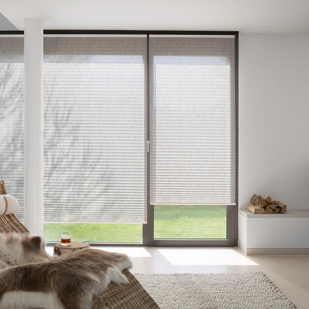 Fein strukturierte Plissee-Vorhänge als lichtdurchlässiger Sonnenschutz vor bodentiefen Fenstern