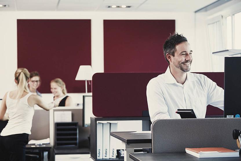 Mitarbeiter im Büro Vier Personen im Büro vor moderner Einrichtung mit weinroten Elementen