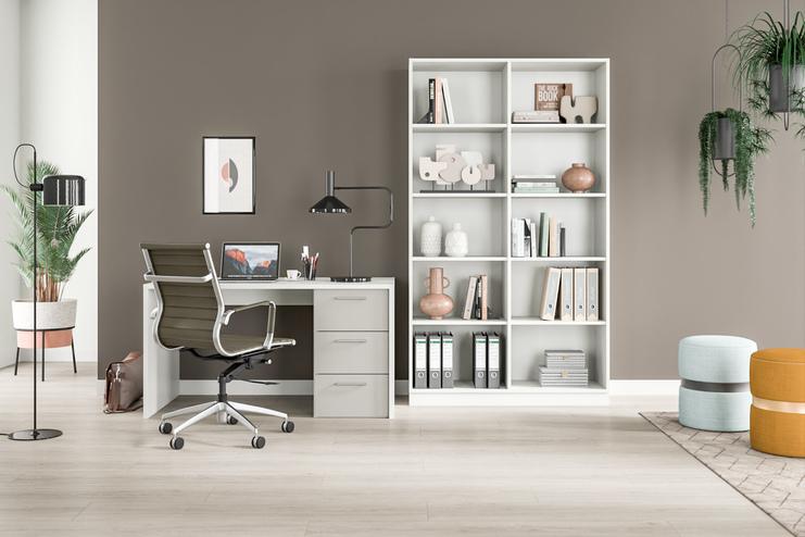 Helles Zimmer mit maßgefertigtem, weißem Regal voller Bücher und Deko, Schreibtisch mit Computer, Pflanzen und Stühlen.